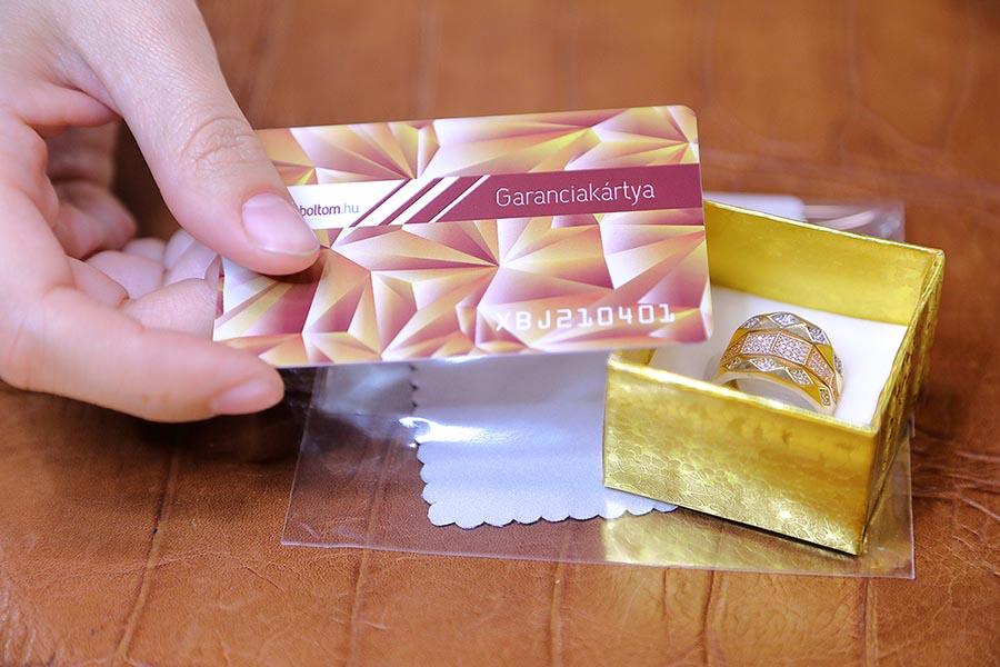 Női kéz plasztikkártyát helyez el a tisztítókendővel és díszdobozzal ellátott ékszer mellé